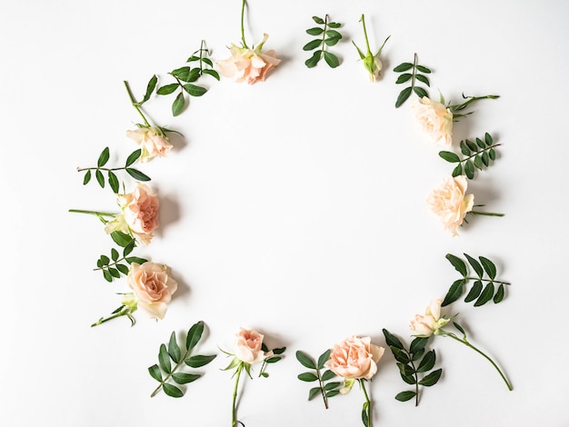 Nature creative round frame of green leaves and roses on a white