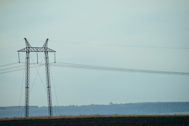 Nature landscape with silhouettes of power lines in field