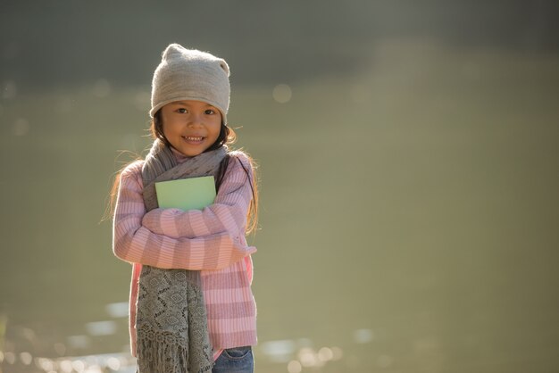 nature little girl, has happy fun with cheerful smiling face. and have a book in hand.