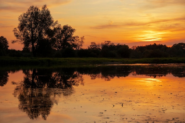 Nature scene of beautiful summer sunset sky and landscape reflecting in calm river