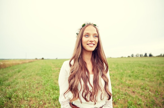 nature, summer, youth culture and people concept - smiling young hippie woman wearing flower wreath on cereal field