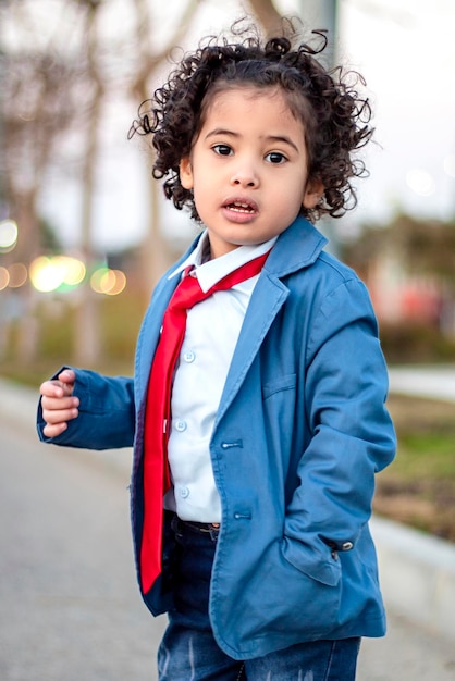 A naughty and handsome little boy, with long hair, elegantly dressed and his hand in his pocket