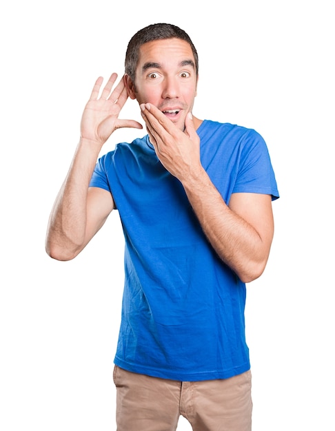 Naughty young man trying to listen against white background