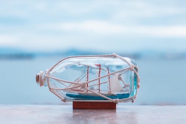 Nautical concept image with sail boat in the bottle on the beach background