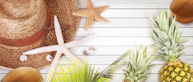 Photo nautical concept with palm leaf, beach hat, starfish and pineapple.