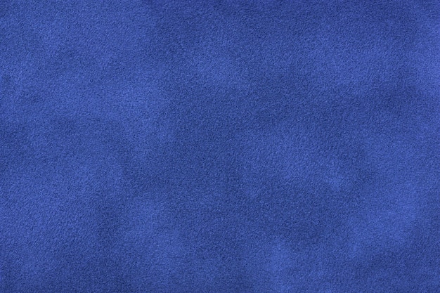 Navy blue matte background of suede fabric, closeup. Velvet texture of seamless sapphire textile, macro. Structure of indigo felt canvas backdrop.