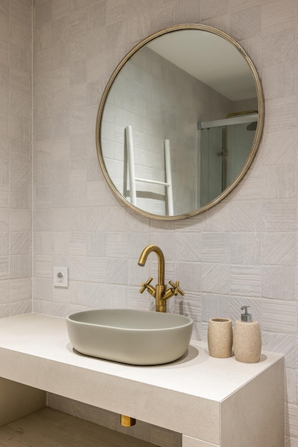 Neat stylish ovalshaped sink on white marble countertop with an elegant coppercoloured faucet above