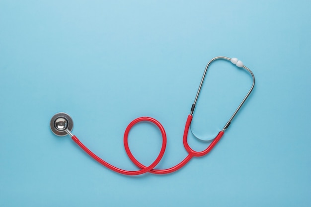 A neatly stacked stethoscope on a blue background. Space for the text. Flat lay.