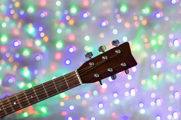 The neck of the acoustic guitar on christmas light bokeh background