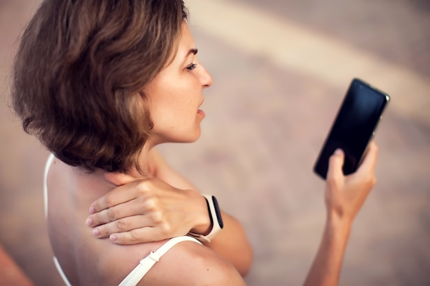 Neck pain using smartphone outdoor. Healthcare, lifestyle and technology concept