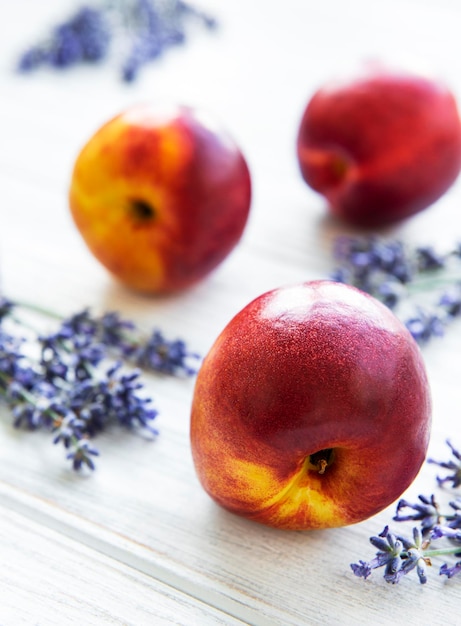 Photo nectarines and flowers of lavender on a white wooden background