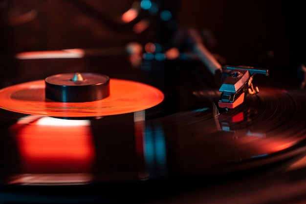 Needle detail on vinyl record on turntable, low light image with reflection