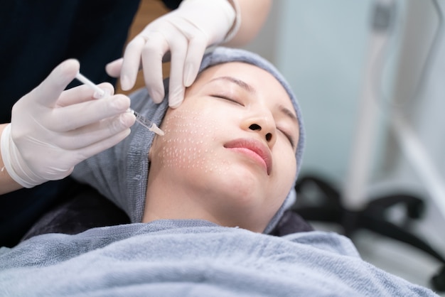 Needle mesotherapy in beauty clinic. Cosmetics injected to woman's face.