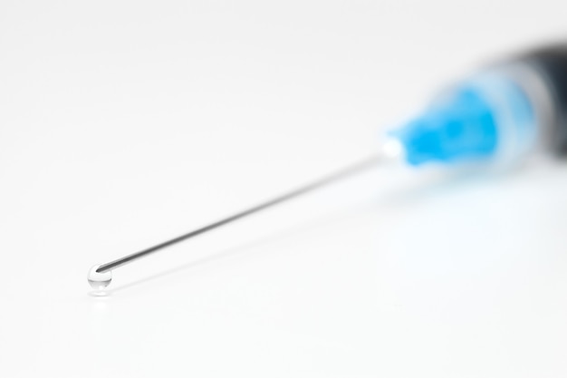 Needle Ñlose-up on syringe and drop of liquid medicine at end.