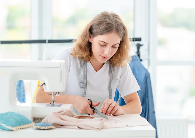 Needlewoman cutting fabric with scissors