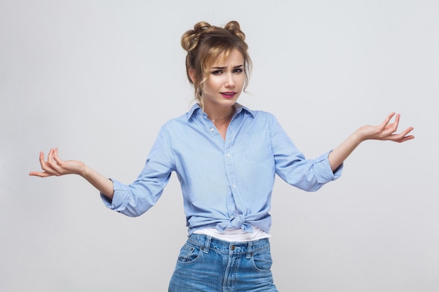 Photo negative human emotions upset young adult woman with hands out shrugging her shoulders