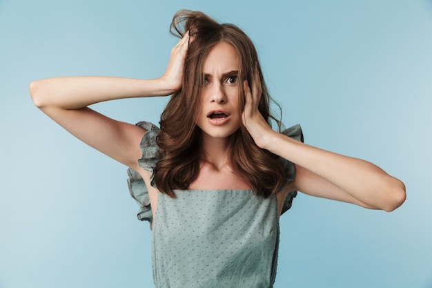 Negative young lady standing isolated over blue