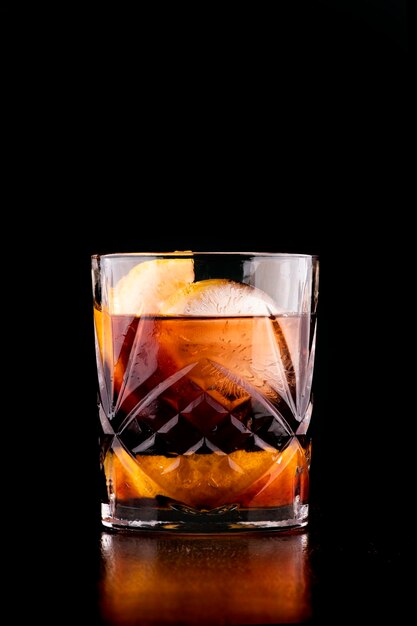 Negroni cocktail with round and orange ice on dark background