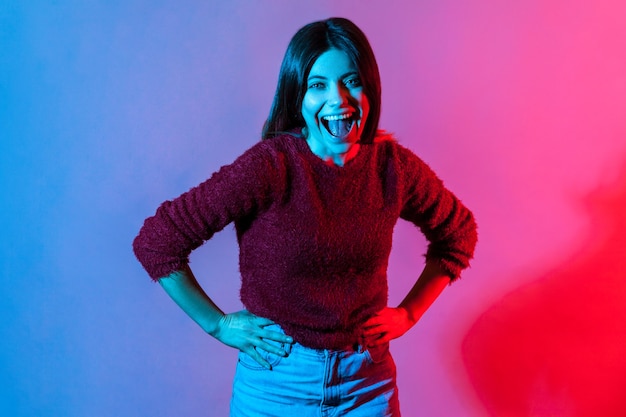 Neon light portrait of joyful carefree woman holding belly and laughing out loud