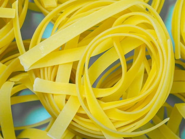 Nests of pasta on a blue background Culinary background Pyramid of noodles Curled pasta on the table Uncooked product Cooking Product made from flour and dough Background from noodles