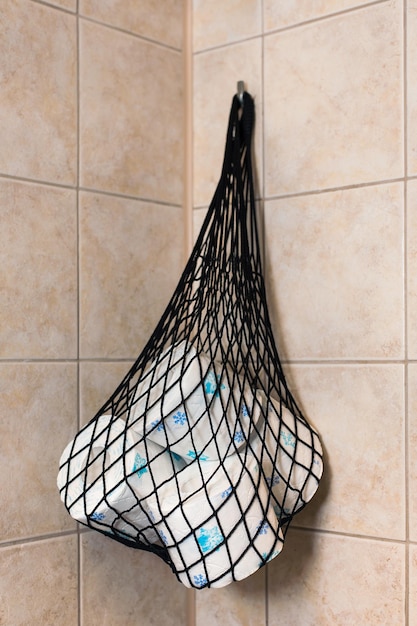 a net with toilet paper rolls hangs on the wall in the bathroom