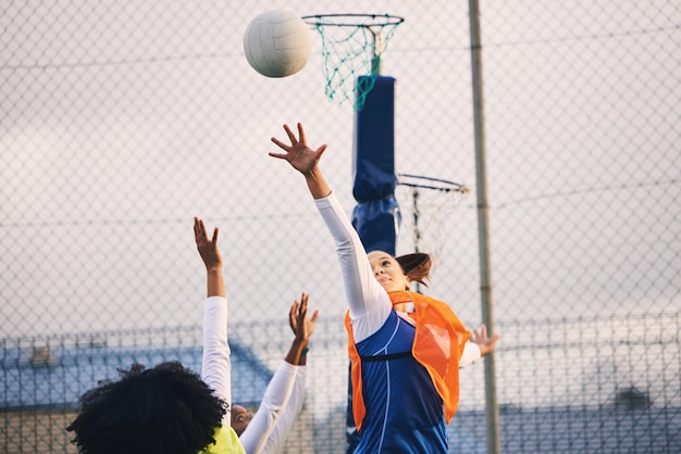 Netball goal shooting and defense of a girl athlete group on an outdoor sports court Aim sport game and match challenge of a black person with a ball doing exercise and training in a competition