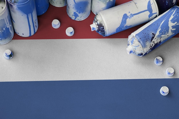 Netherlands flag and few used aerosol spray cans for graffiti painting Street art culture concept