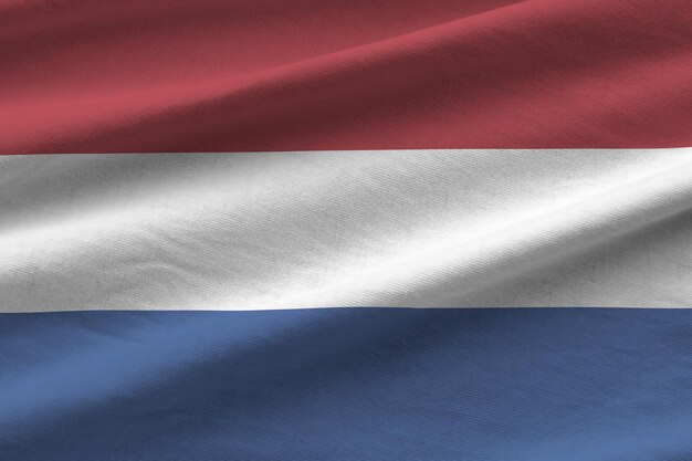 Netherlands flag with big folds waving close up under the studio light indoors The official symbols and colors in banner