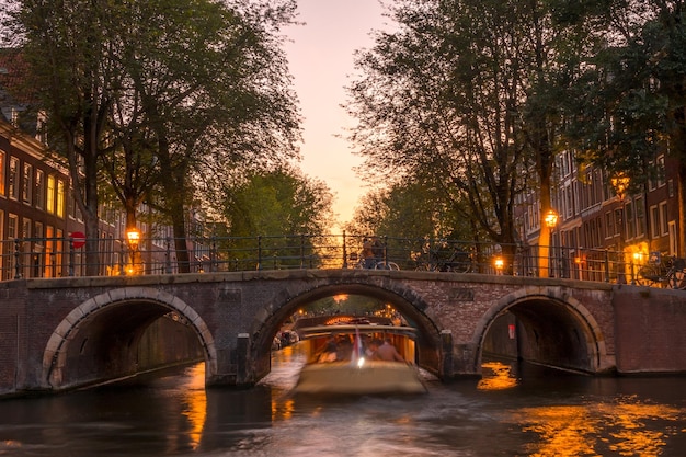 Netherlands Pink sunset on the Amsterdam Canal Pleasure boat under the stone bridge