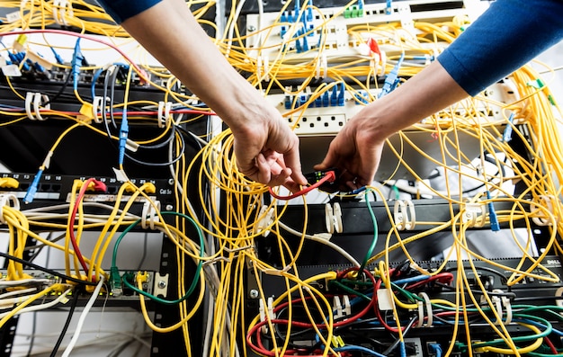 Network engineer working in server room. Connecting network cables to switches