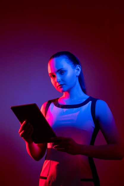 Network security Cyberspace privacy Future technology Digital information safety Confident neon light woman with tablet in pink blue fluorescent glow isolated on dark purple red