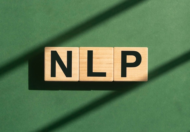 Neurolinguistic programming NLP acronym on wooden cubes blocks on green background