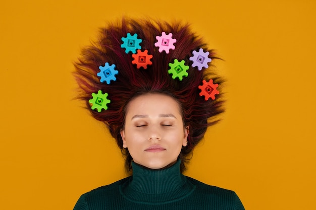 Neurophysiology, neuroscience, Brain, psychology, mental health, creativity, idea concept. Woman with gears in hair on orange background.