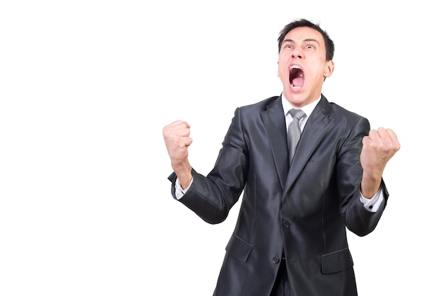 Neurotic male in elegant suit screaming and looking up with clenched fists while celebrating isolated on white background in light studio