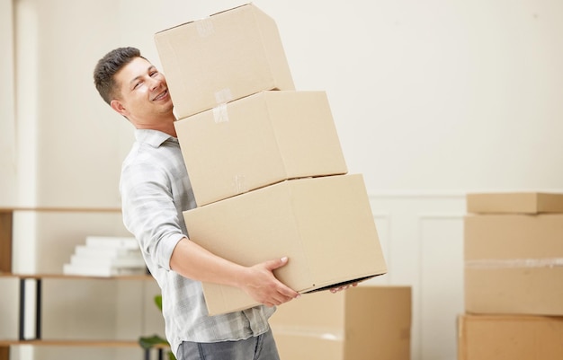 Never been this happy to move boxes. Shot of a handsome young man carrying boxes into his new home.