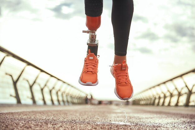 Never give up cropped photo of disabled woman with prosthetic leg in sportswear jumping on