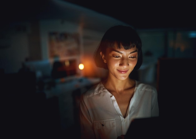 Never without the latest business news Shot of a young businesswoman using a digital tablet during a late night at work