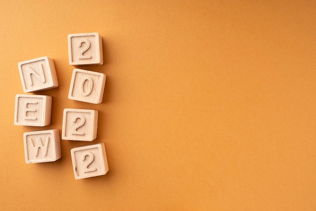 The new 2022 is written on wooden cubes Wooden cubes with letters and numbers on an orange background New Year's card