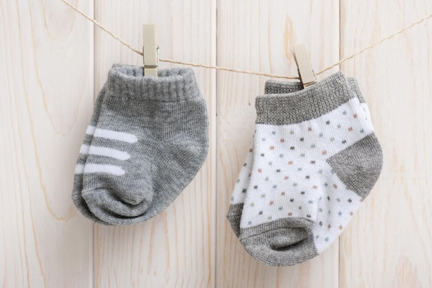 New baby socks hanging on clothesline over wood background newborn and baby concept