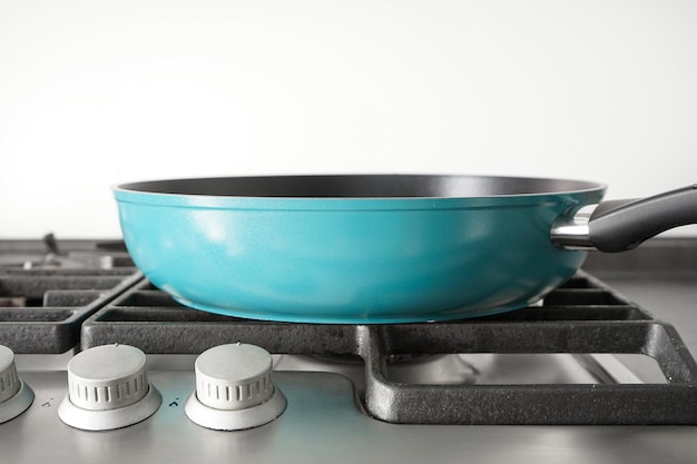 New blue frying pan on the gas stove Closeup