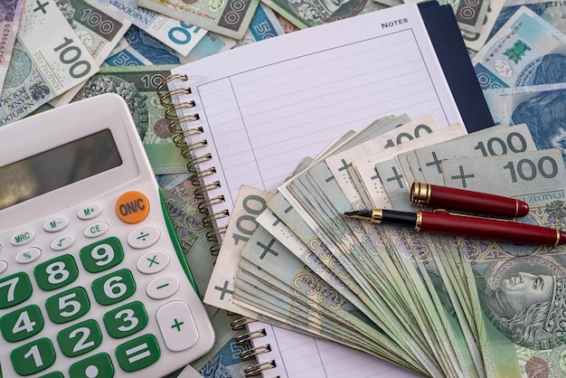 new calculator notebook for business records red pen on the background of pottery zloty banknotes. Business concept