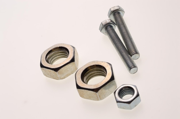 New chromeplated bolts and nuts of different sizes lie on a white background Closeup