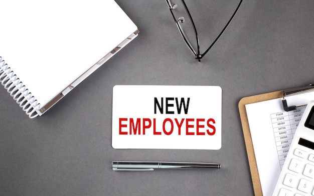 NEW EMPLOYEES Text written on the card with notebook and clipboard grey background