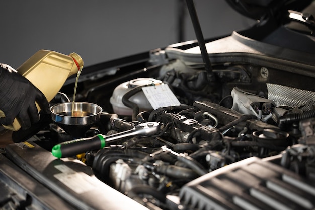 New engine oil is poured into the engine replacement of technical fluids of the car close up of pour