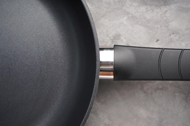 New frying pan and kitchen towel on a gray background closeup Top view flat lay