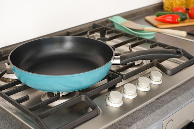 New frying pan on the stove and fresh vegetables lie near the frying pan on the countertop