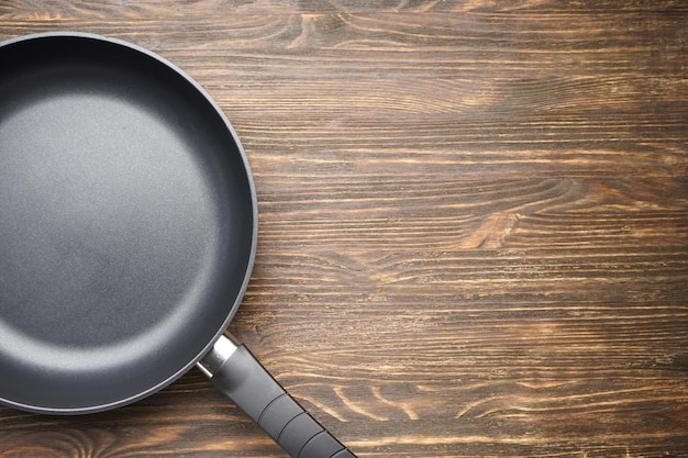 New frying pan on a wooden background space for text Top view flat lay