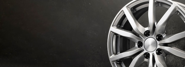 New grey alloy wheels on a dark textured black background car wheel  copy space panorama empty space