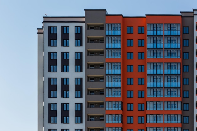 New high rise apartament building with multiple balcony and windows on blue sky with white clouds background