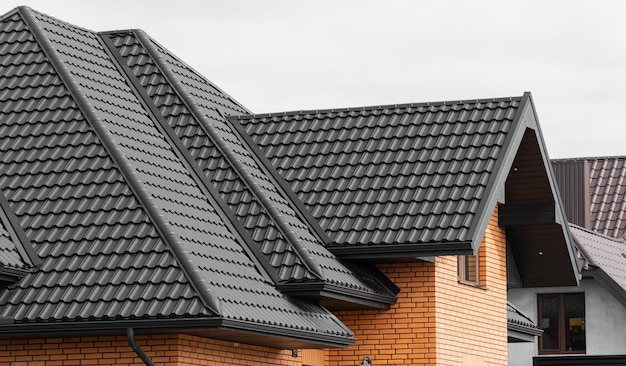 A new house made of yellow bricks and a beautiful black roof Black corrugated metal profile roof installed on a modern house